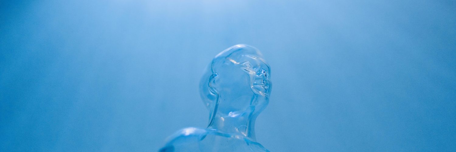 Transparent figure against a blue sky, symbolizing futuristic concepts and technology.